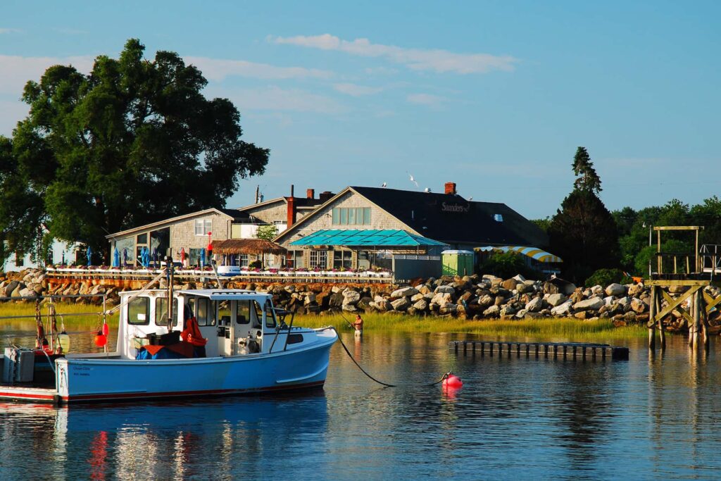 Boats are moored near a waterfront café on a calm summer day in Rye NH
